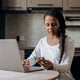 African American woman using laptop and credit card for online shopping at home.